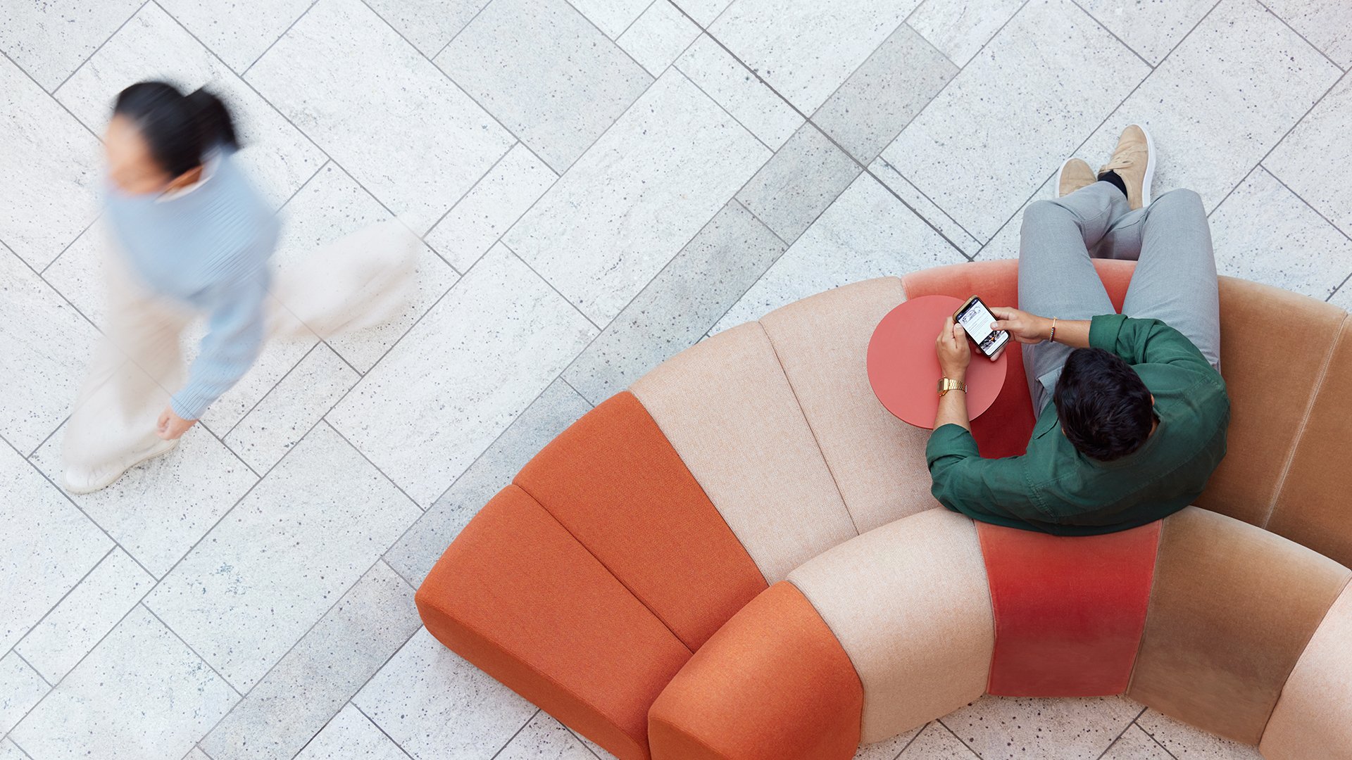 a man and woman sitting on a couch looking at a cell phone