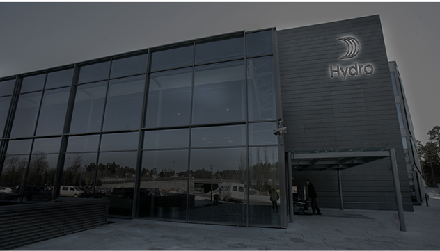 dark building with a backlit logo placed near top right corner above entrance canopy