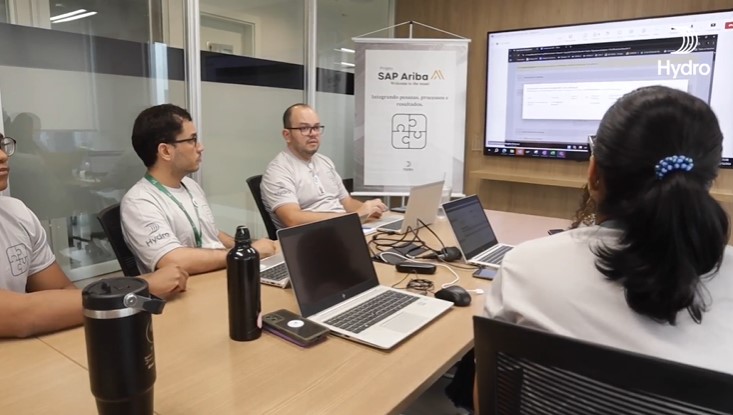 a group of people sitting at a table with laptops