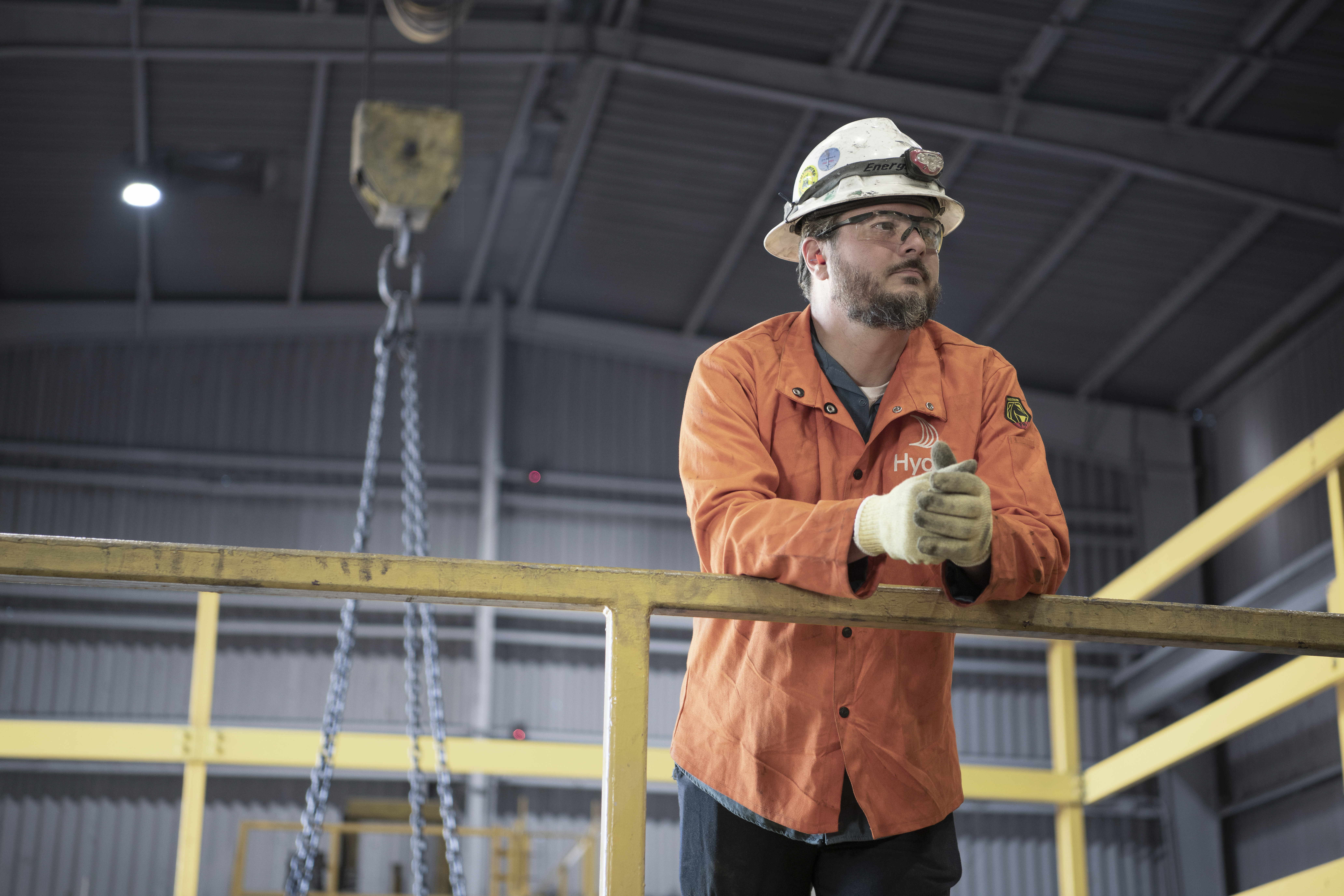 A Hydro colleague wearing a safety helmet leaning on a handrail at Hydro's Phoenix plant