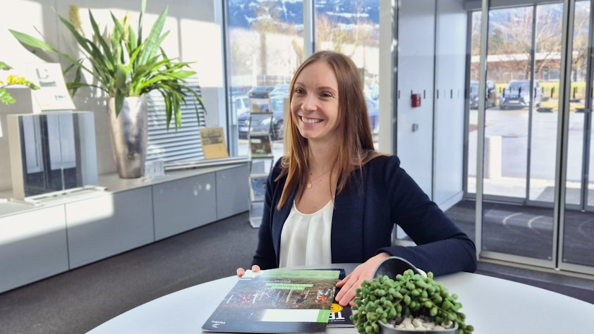 a woman sitting at a table with a plant and a book