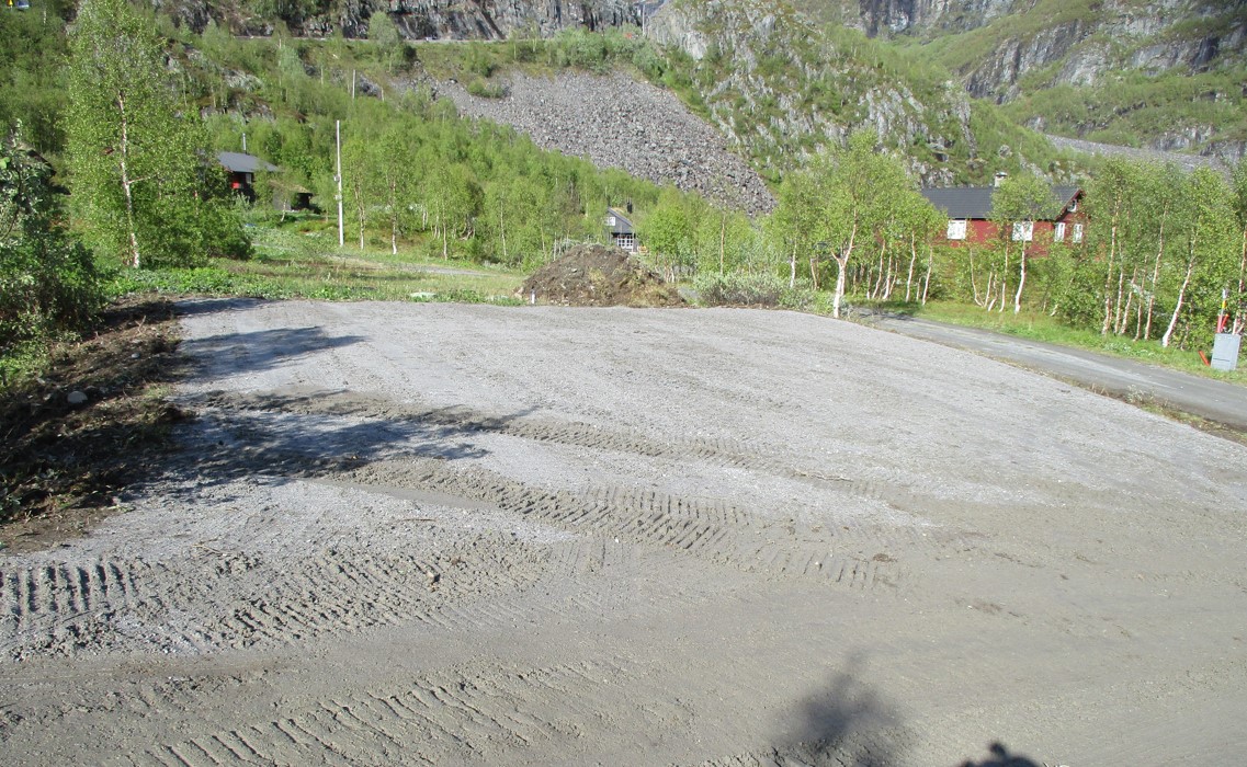 a dirt road with a house on the side