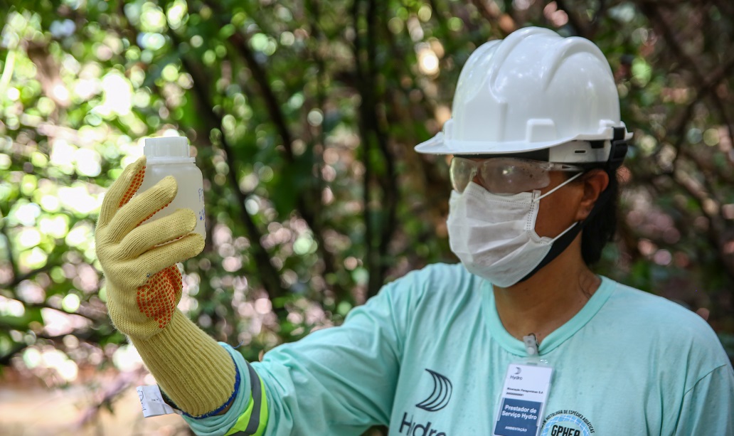 a man wearing a hard hat and gloves holding a bottle of water